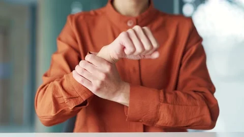 Close up of a woman's hand massaging her wrist while sitting at a workplace at  Stock Footage 239026331