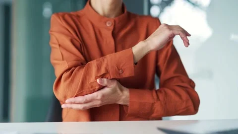 Close up. Woman's hand massaging her elbow, stretches her arm while sitting at  Stock Footage 239026354