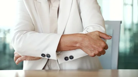 Close up. Woman's hand massaging her elbow while sitting at a workplace  Stock Footage 262062687