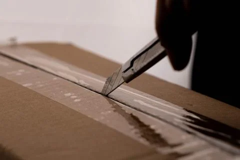 Close-up of woman's hand opening box using cutter. Hands unpacking cardboard box Stock Photos