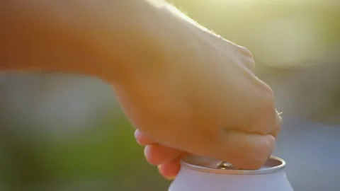 Close-up of woman's hand opening cans of cold beer with bokeh nature background. Video stock 263726823