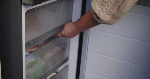 Close-up of a womans hand opening a modern freezer door, pulling out a drawer Stock Footage 329858804
