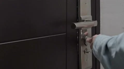 A close-up of a woman's hand opens the metal black door to the apartment with a Stock Footage 212473206