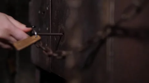 A close-up of a womans hand opens an old rusty metal door with an antique key. Stock Footage 311154568