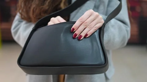 Close-up of a woman's hand with painted nails, holding a black handbag. Stock Footage 292918152