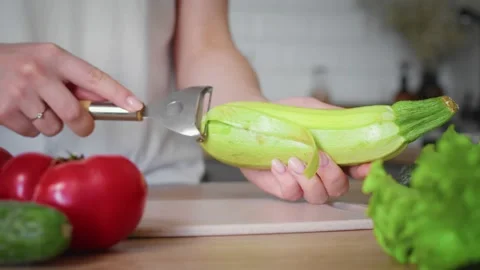 Premium Photo  Peeling fresh green zucchini with peeler. process of  cleaning raw squash with a vegetable peeler.