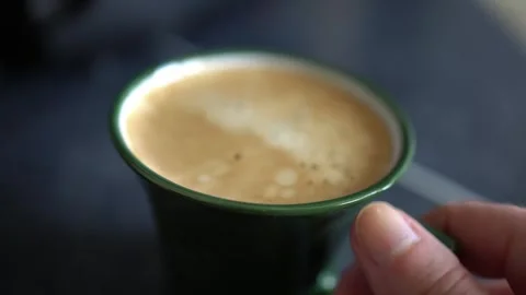 A close-up of a woman's hand picking up freshly made coffee from the table. Stock Footage 309190259