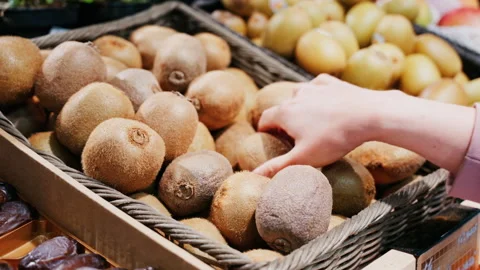 Close up of a woman's hand picking up kiwis at a market Stock Footage 311567462
