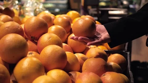 Close-up of a woman's hand picking up large ripe oranges from a counter  Stock Footage 270518970