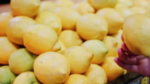Close up of a woman's hand picking up lemons at a market Stock Footage 311567210