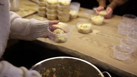 Close-up of woman's hand picking rice porridge from large jar in plastic bowls Stock Footage 172548255
