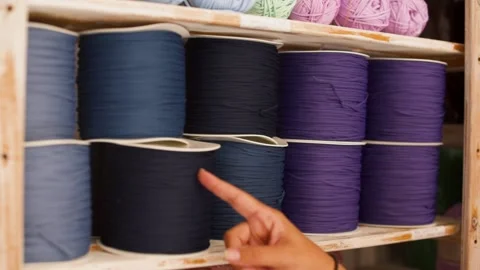 Close-up of woman's hand picking spool of thread from shelf Stock Footage 130605305