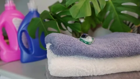 Close-up of a woman's hand placing a detergent capsule on a towel, with bleach a Stock Footage 295285962