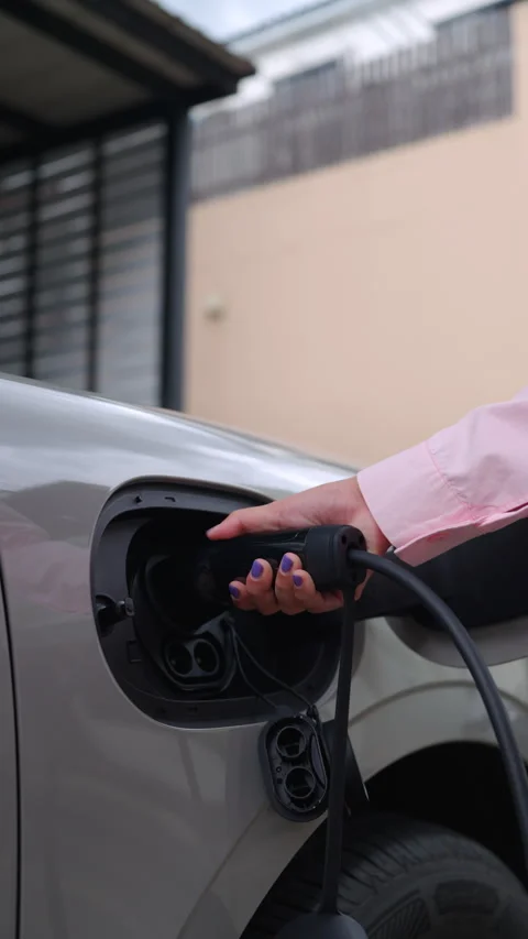 Close-up of an woman's hand plugging a charger into an electric car. Vídeos de archivo 346871383