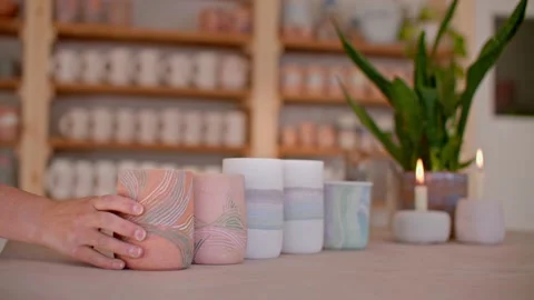 Close up a womans hand in pottery studio placing homemade mugs for display 库存影片 221949544