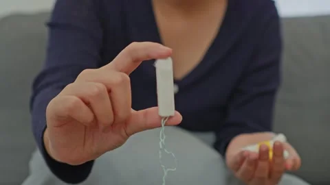 Close up of woman's hand presenting clean white tampon with hanging string Stock Footage 340576499