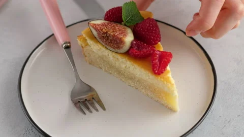 Close-up. A woman's hand puts a mint leaf on a piece of cheesecake with berries Video stock 153418047