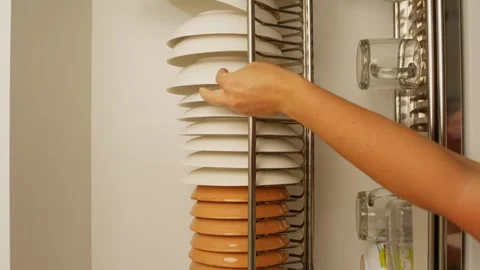 Close-up of a woman's hand putting clean dishes in a drawer in the kitchen. Stock Footage 281745174