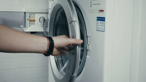 Close-up of woman's hand putting clothes in washing machine from Laundry basket. Stock Footage 101344251