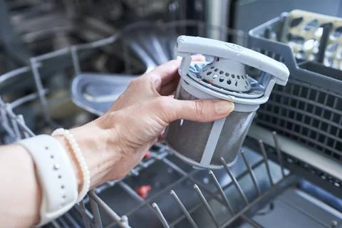 Close-up of a woman's hand putting a filter in the dishwasher. Stock Photos