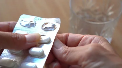 Close-up of a woman's hand removing a tablet out of a blister pack Stock Footage 277497479