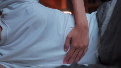 Close-up of a woman's hand resting on her stomach while lying in bed at night Vídeo Stock 347147306