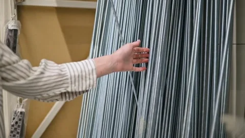 Close-up of a woman's hand selecting steel rods in a hardware store Stockbeeldmateriaal 344526505
