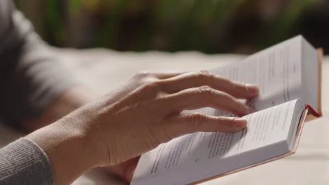 Close-up, womans hand sliding over the page of an open book in search of the Stock Footage 315368212