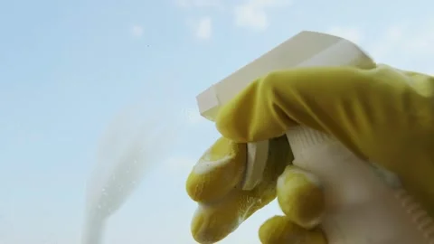 Close-up of a woman's hand spraying cleaning solution on a window to remove dirt Stock Footage 301307662