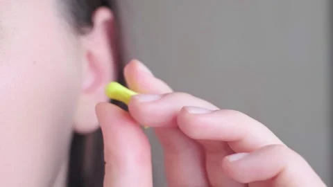 Close-up of a woman's hand squeezing earplugs before inserting them into the ear Stock Footage 296575772