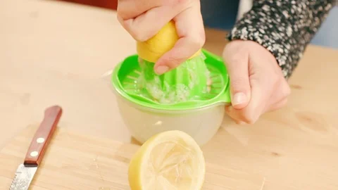 Close up of a woman's hand squeezing lemon on wooden table Stock Footage 121295842