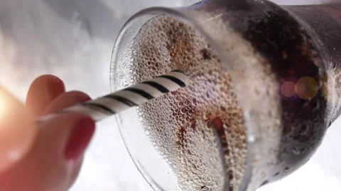 Close up of a woman's hand stirring a soft drink and ice cubes with a straw Stock Footage 165198211
