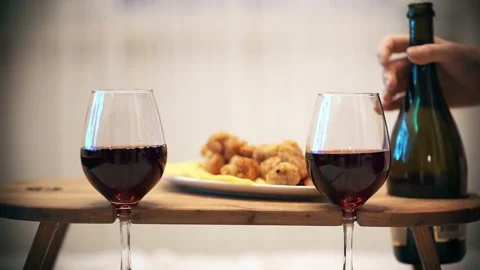 Close-up of a woman's hand, a table with fancy glasses and a bottle of wine. Vidéo 200248423