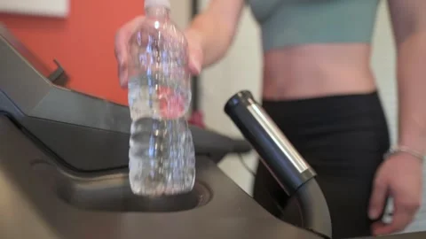 Close-up of a woman's hand take a water bottle from the treadmill, with a focus Vidéo 277617151