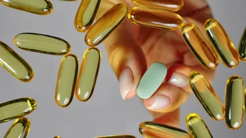 Close-up of a woman's hand taking a lonely pill from a pile of fish oil capsules Stock Footage 267420795