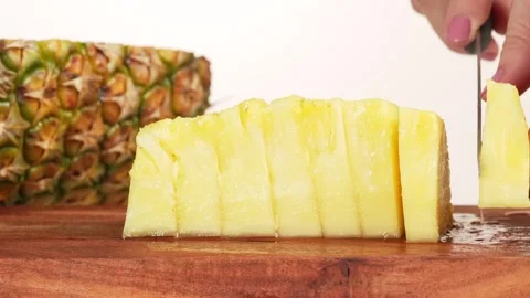 Close-up of a womans hand taking pineapple slices from a wooden cutting boa.. Vídeos de archivo 314431341