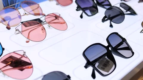 Close-up womans hand taking sunglasses from store window. Window displays dozens Video stock 257667330