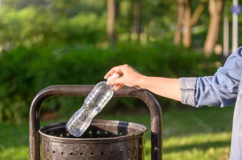 Close-up of a woman's hand throwing an empty plastic bottle Stock Photos