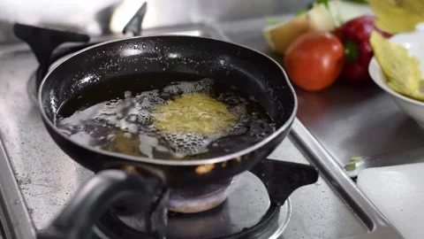 Close-up of a woman's hand, throwing flattened pieces of plantain into the .. Stock Footage 248728812