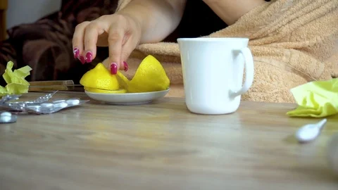 Close - up of a woman's hand throwing a piece of lemon into a Cup of tea Stock Footage 116995807