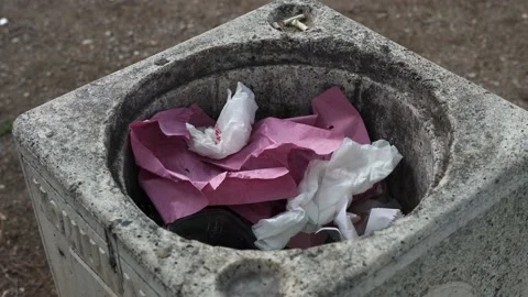 Close-up of a woman's hand throws a pink crumpled piece of paper into a concrete Stock Footage 197028787