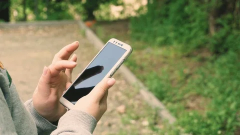 Close up of woman's hand touching mobile phone at night with urban blurred Stock Footage 107344114