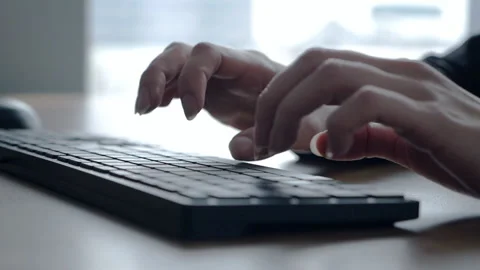 Close-up of a woman's hand using and typing on a keyboard in the office. Slow Stock Footage 153933615