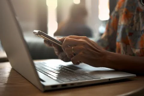 Close-up of woman's hand using smartphone while working on laptop in a coffee Stock-Fotos