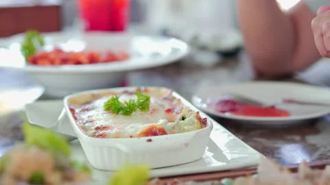Close-up of a woman's hand using a spoon to scoop baked spinach lasagna Video stock 212093676