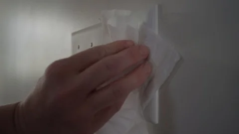 Close up of a woman's hand using a wet wipe to clean off light switches Stock Footage 128920563
