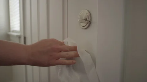 Close up of a woman's hand using a wet wipe to clean off door knob Stock Footage 128920598