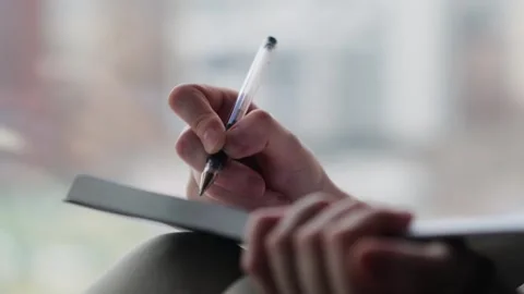 Close-up of woman's hand writing in a journal her goals and dreams. Stockbeeldmateriaal 270509414