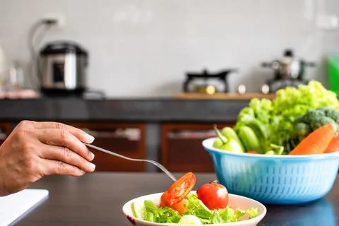 Close-up, Woman's handheld a fork to scoop chopped vegetables in a cup on w.. Stock Photos