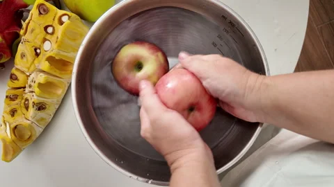 Close-up of a womans hands in an apron, standing in front of a table with fruit Stock Footage 319095318